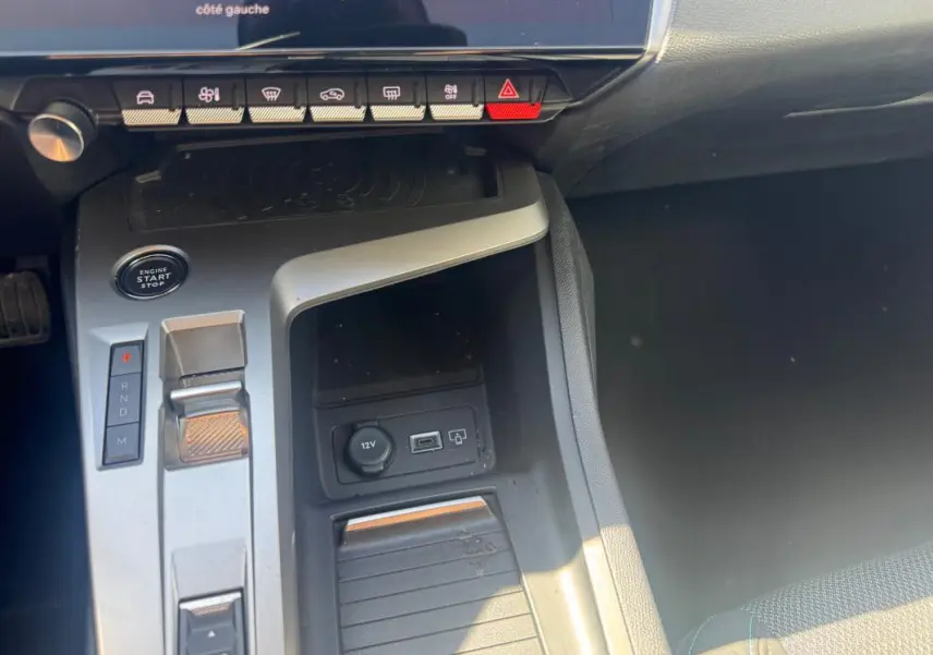 Vue rapprochée de la console centrale grise de la Peugeot 308 Hybrid 136 e-DCS6 Allure avec levier de vitesse automatique et boutons de commande.