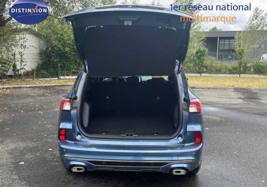 Vue arrière d'un Ford Kuga 2024 bleu chrome métal avec coffre ouvert et double sortie d'échappement visible.