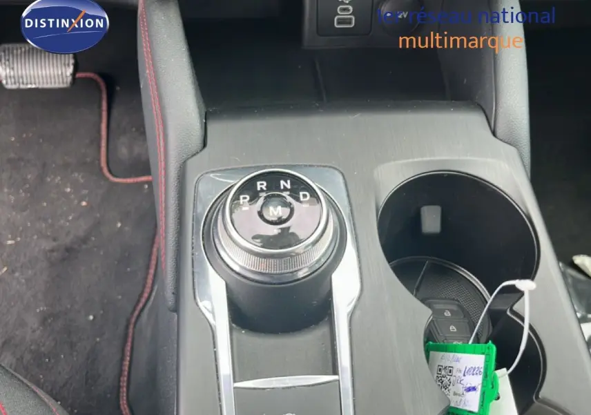 Vue rapprochée de la console centrale du Ford Kuga 2024 bleu chrome, avec molette de boîte auto et porte-gobelets.