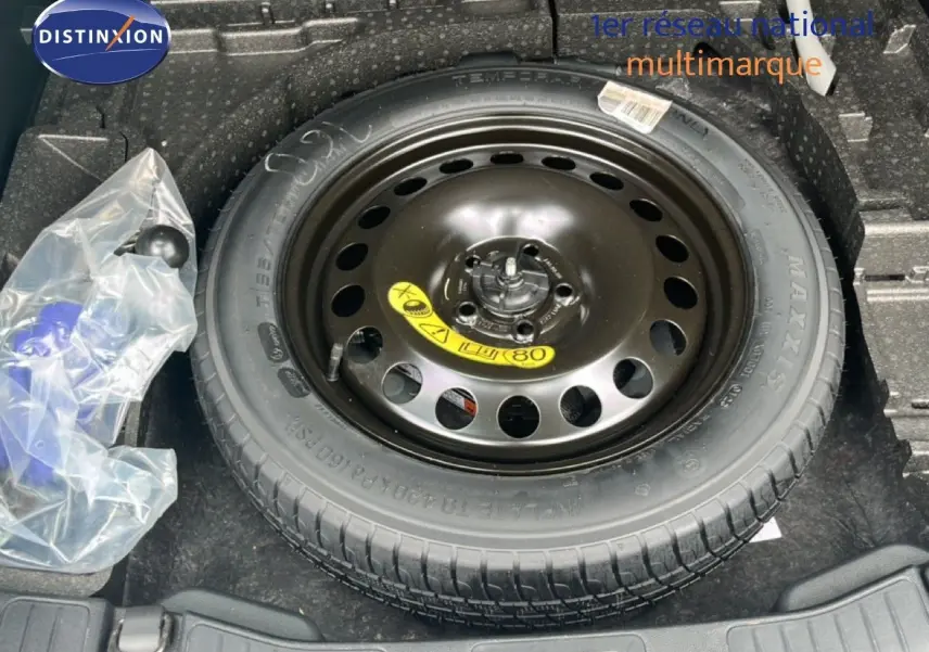 Vue plongeante sur la roue de secours noire dans le coffre d'un Ford Kuga bleu chrome métal 2024.