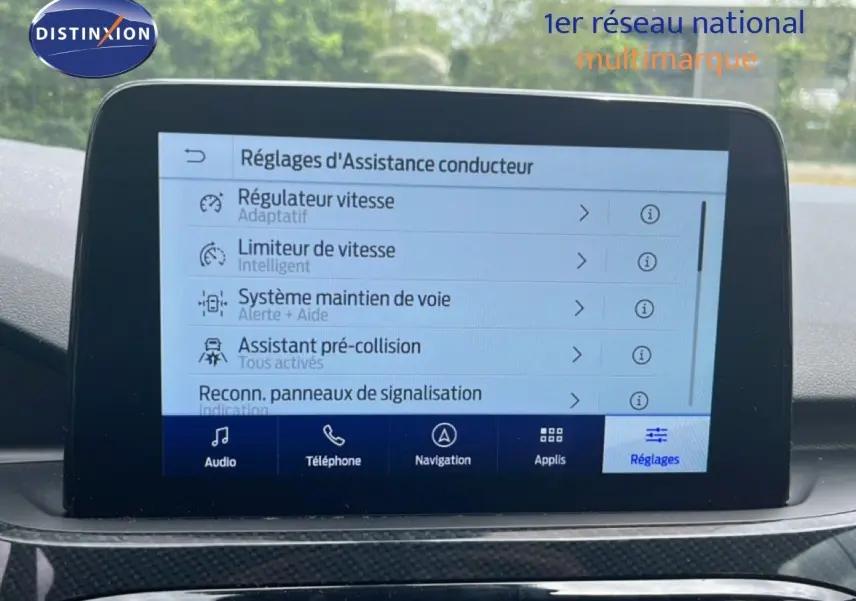 Écran tactile central affichant les réglages d’assistance conducteur dans un Ford Kuga bleu chrome métal, vue intérieure frontale.