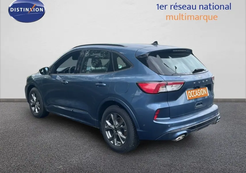 Vue 3/4 arrière droite d'un Ford Kuga 2024 bleu chrome métal avec jantes alliage et double sortie d'échappement.