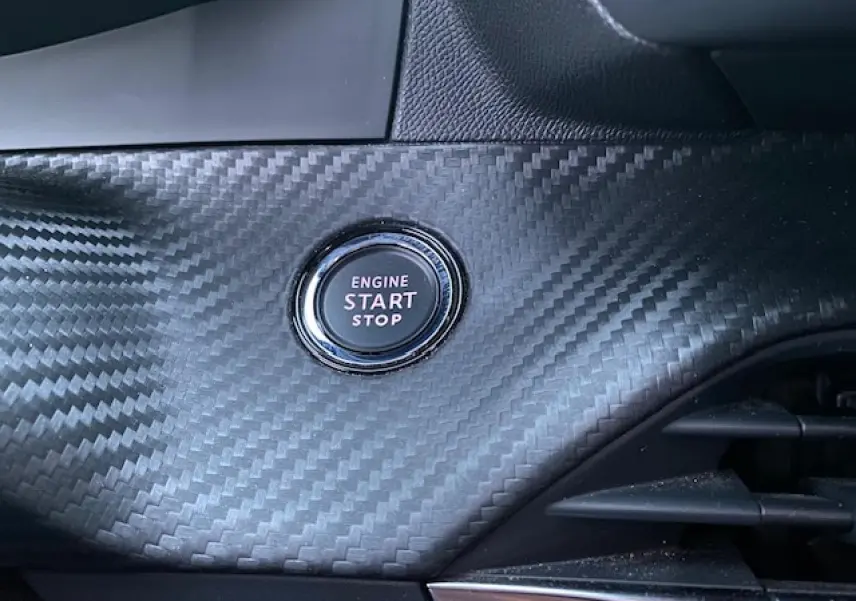 Bouton démarrage moteur "Engine Start Stop" sur tableau de bord en carbone du Peugeot 2008 blanc, vue intérieure rapprochée.