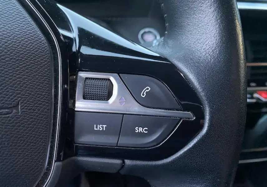 Gros plan sur les commandes gauche du volant en cuir noir du Peugeot 2008 blanc de 2020.