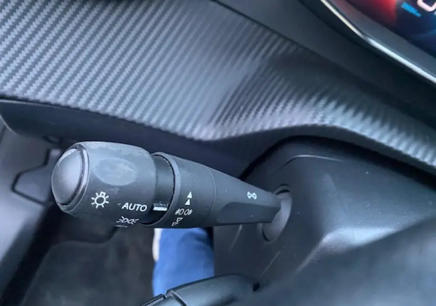 Gros plan sur la manette des feux avec réglage automatique dans l'habitacle du Peugeot 2008 blanc 2020.