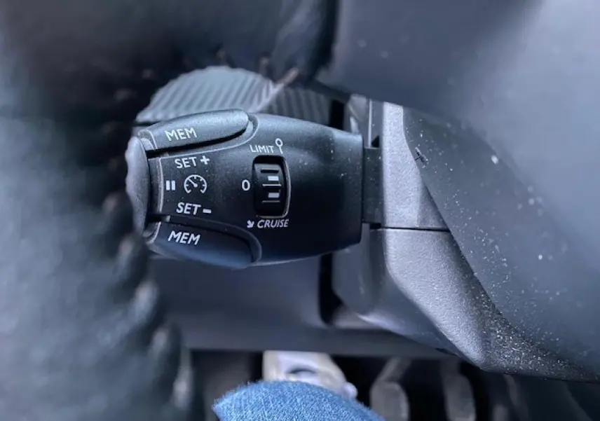 Gros plan sur la commande de régulateur de vitesse au volant d'un Peugeot 2008 blanc de 2020.
