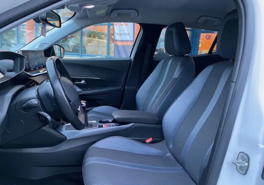 Intérieur avant droit du Peugeot 2008 blanc 2020, sièges tissu gris à surpiqûres bleues et tableau de bord moderne.
