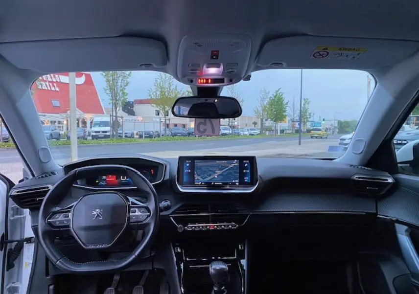 Vue intérieure avant du Peugeot 2008 blanc de 2020, avec tableau de bord moderne et écran tactile de navigation.