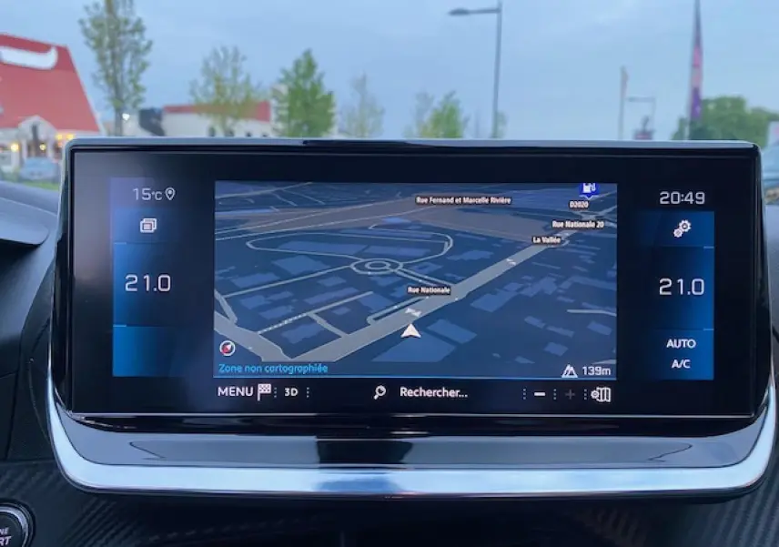 Écran tactile 7 pouces du système de navigation 3D du Peugeot 2008 blanc, affichant une carte de rue en soirée.