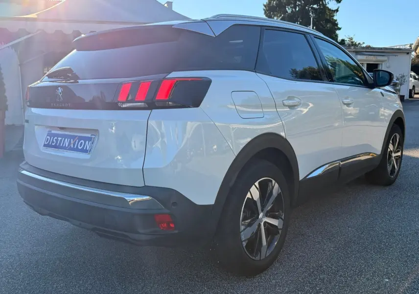 Vue 3/4 arrière droite d'un Peugeot 3008 blanc nacré avec feux arrière à trois griffes et jantes alliage bicolores.