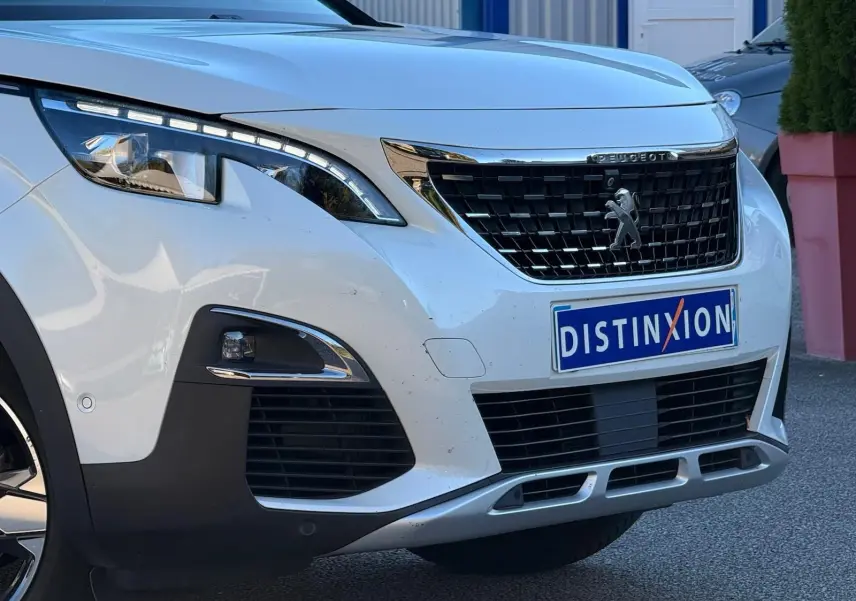Vue de face rapprochée du Peugeot 3008 blanc nacré mettant en valeur sa calandre noire et ses phares LED distinctifs.