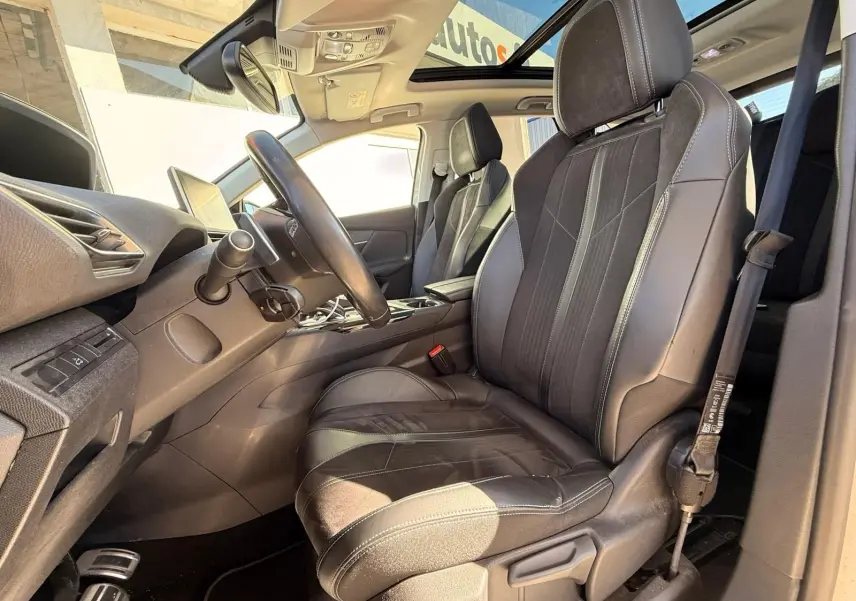 Intérieur du Peugeot 3008 2019, vue côté conducteur, sièges en cuir noir avec surpiqûres blanches et toit ouvrant panoramique.