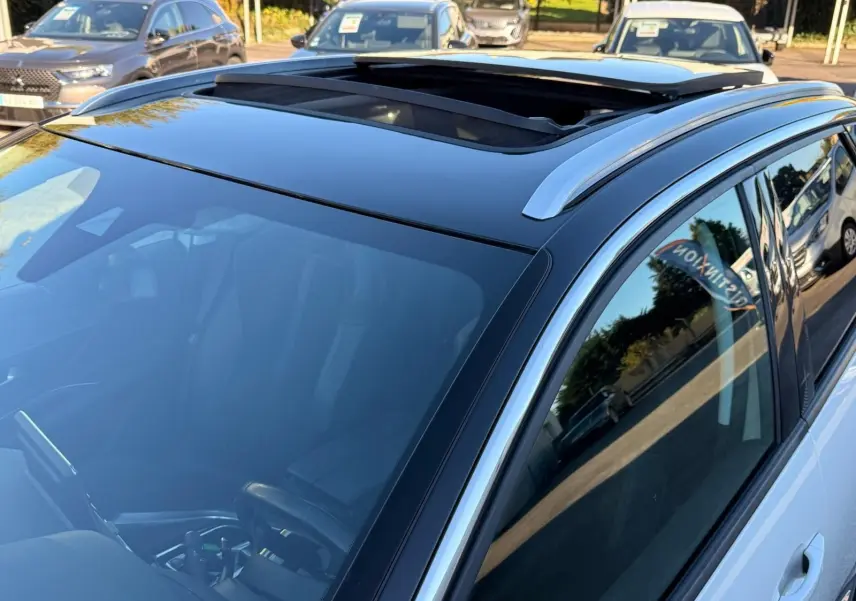 Vue rapprochée du toit ouvrant panoramique et du côté droit du Peugeot 3008 blanc nacré stationné en extérieur.