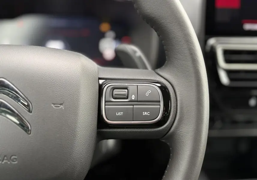Gros plan sur les commandes gauche du volant noir du Citroën C5 Aircross Hybrid 2025 avec boutons multifonctions.