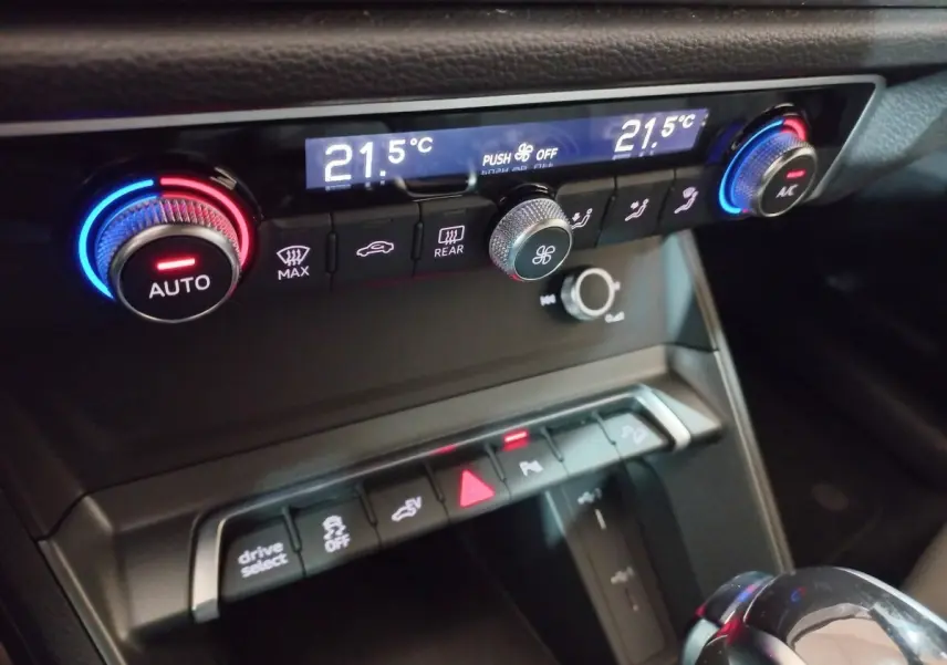 Gros plan sur la console centrale de l’Audi Q3 blanc, montrant les commandes de climatisation et les boutons multifonctions.