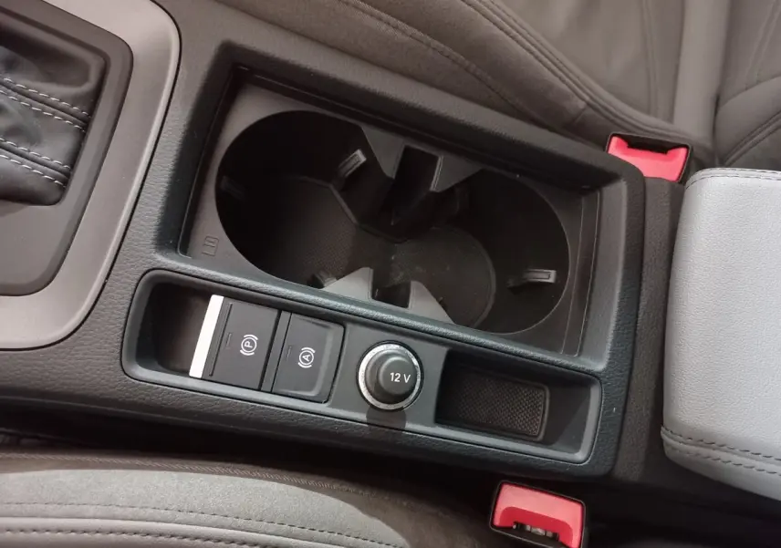 Gros plan sur la console centrale noire avec porte-gobelets et commandes 12V de l'Audi Q3 blanc 45 TFSI E S Line.