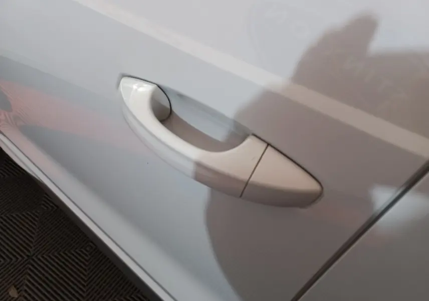 Poignée de porte blanche en gros plan sur le côté gauche d’un Audi Q3 45 TFSI e S line hybride rechargeable.