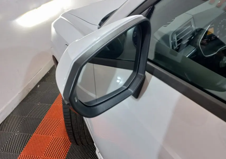 Rétroviseur droit gris sur Audi Q3 blanc hybride rechargeable, vue rapprochée côté avant droit avec intérieur partiellement visible.