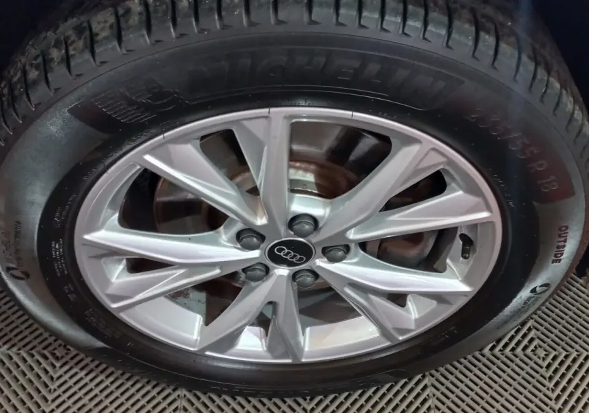 Gros plan sur la jante alliage argentée avec logo Audi au centre, montée sur pneu Michelin, vue de face.