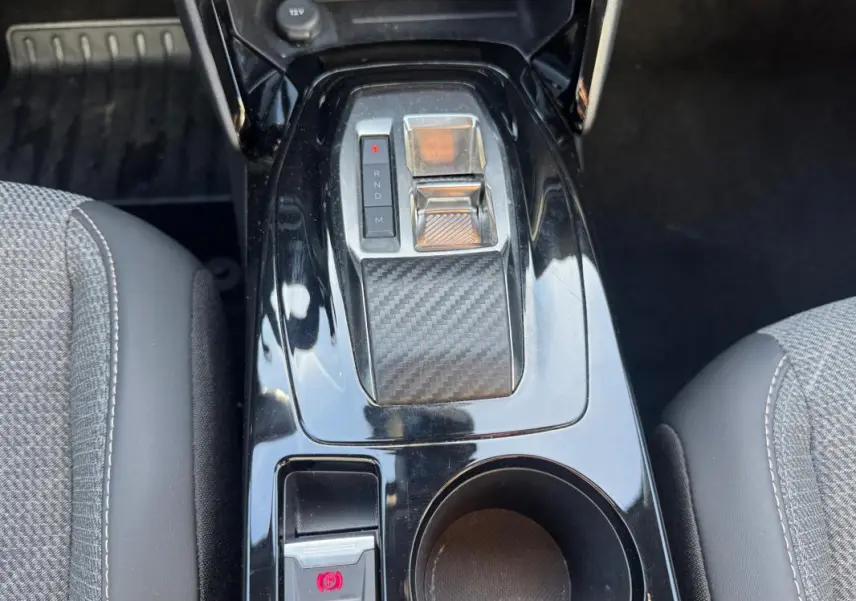 Vue rapprochée de la console centrale noire du Peugeot 2008 Hybrid 136 e-DCS6 Allure avec levier de vitesses automatique et frein à main électronique.