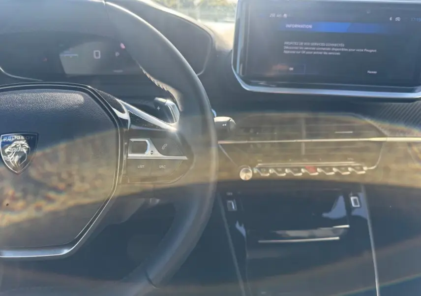 Intérieur du Peugeot 2008 Hybrid 136 Allure 2025, vue sur le volant noir et l'écran tactile central avec commandes modernes.