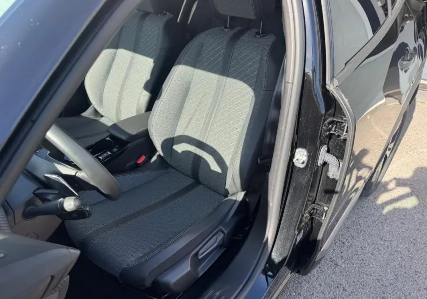 Vue intérieure côté conducteur du Peugeot 2008 Hybrid noir 2025, mettant en valeur le siège avant et la portière ouverte.