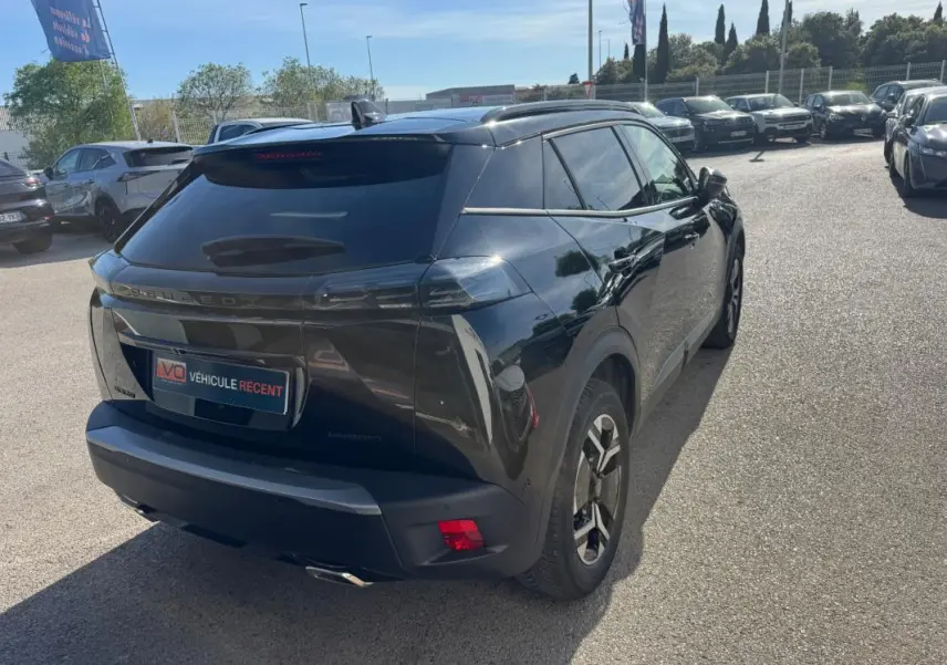 Peugeot 2008 Hybrid noir en 3/4 arrière droit, avec barres de toit et jantes alliage 17 pouces visibles.