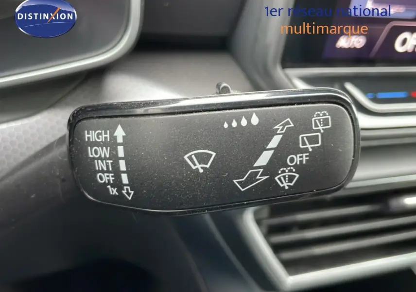 Gros plan sur la commande d’essuie-glace du SEAT LEON gris magnétique, avec tableau de bord flou en arrière-plan.