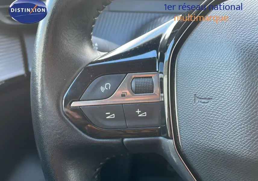 Gros plan sur les commandes au volant côté gauche d'une Peugeot 208 électrique gris Artense de 2020.