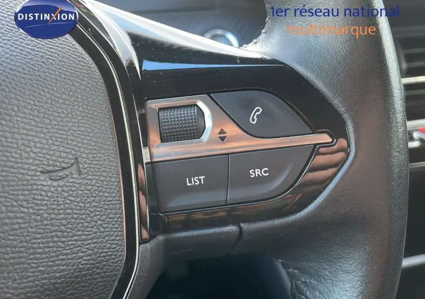 Gros plan sur les commandes multifonctions à droite du volant d'une Peugeot 208 électrique gris Artense, version Active Business.