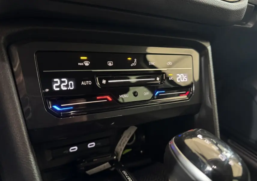 Vue rapprochée de la console centrale du Volkswagen Tiguan bleu 2021, montrant la climatisation digitale et le levier de vitesse.