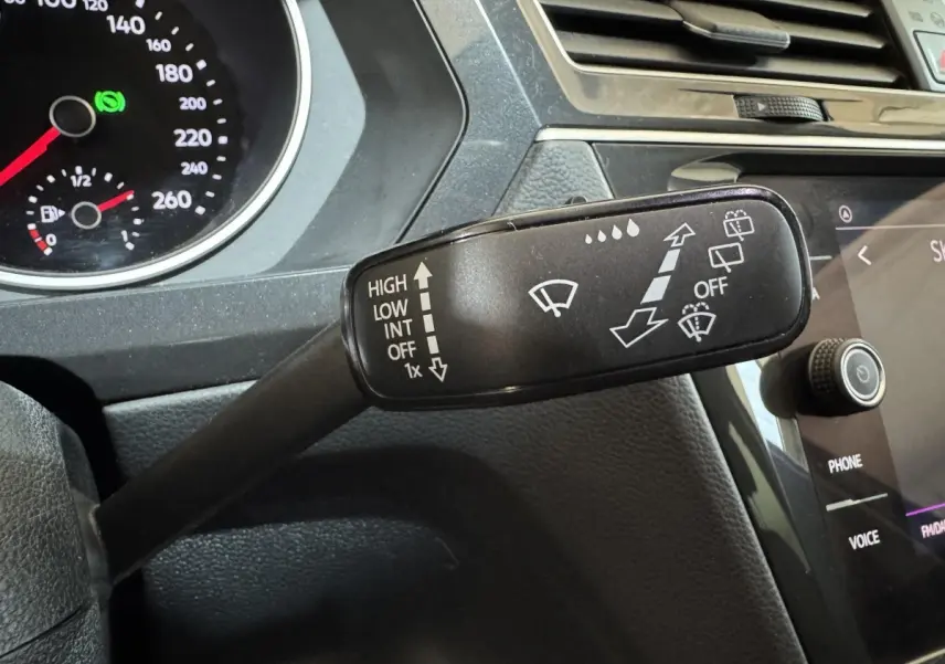 Gros plan sur la commande des essuie-glaces du Volkswagen Tiguan bleu 2021, tableau de bord et écran tactile visibles.