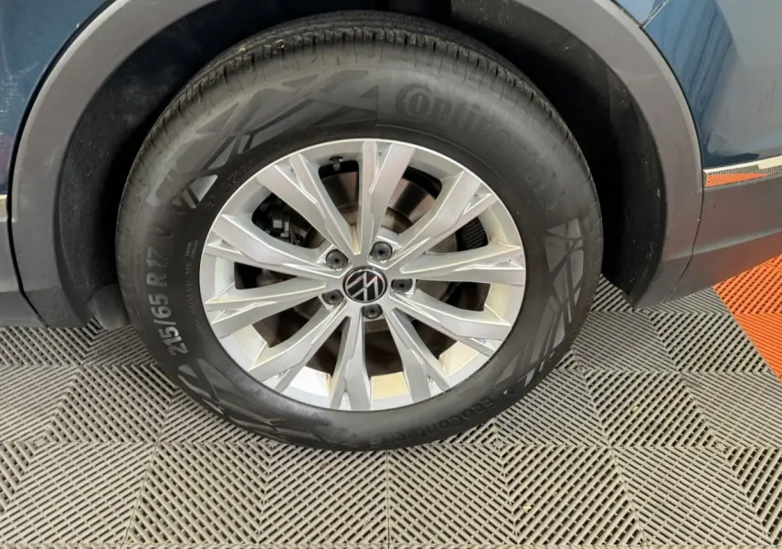 Gros plan sur la roue avant droite du Volkswagen Tiguan bleu, avec jante alliage argentée et pneu Continental.