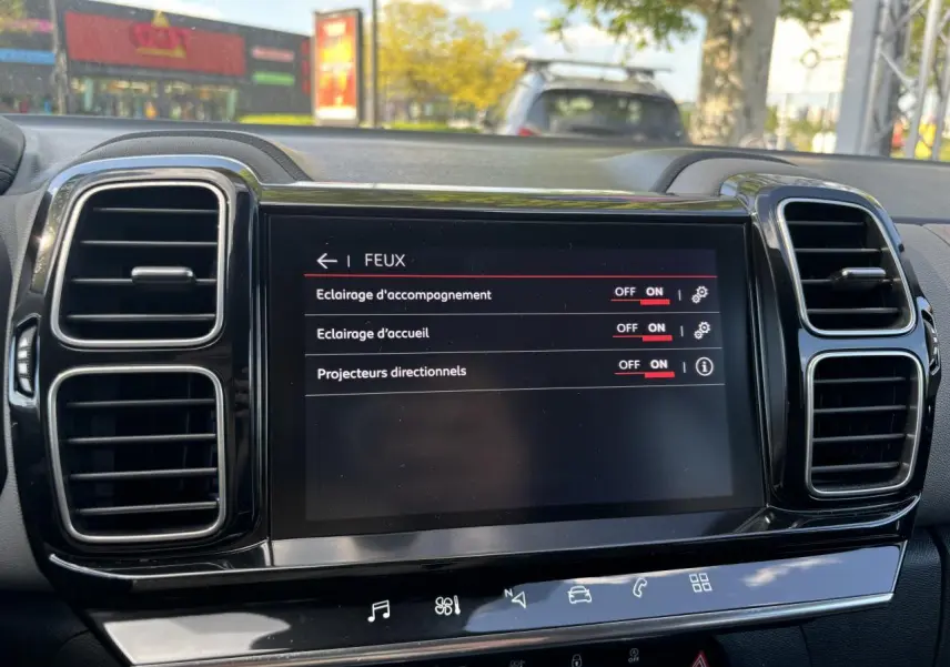 Écran tactile central du tableau de bord du Citroën C5 Aircross 2019, affichant les réglages des feux, entouré de grilles d'aération noires.