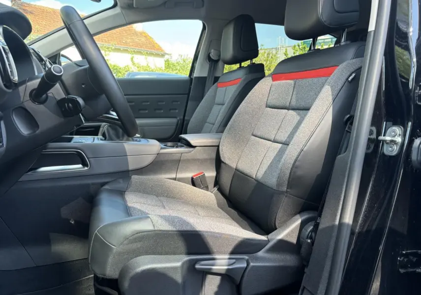 Vue intérieure côté conducteur du Citroën C5 Aircross noir métallisé, mettant en valeur les sièges Advanced Comfort gris avec bande rouge.