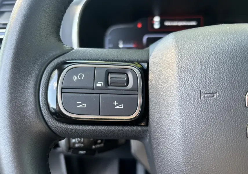 Gros plan sur les commandes au volant à gauche du Citroën C5 Aircross noir métallisé de 2019.