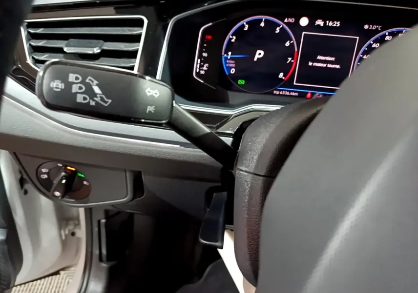 Vue rapprochée du tableau de bord et du volant de la Volkswagen Taigo blanc, avec affichage digital et commandes au volant visibles.