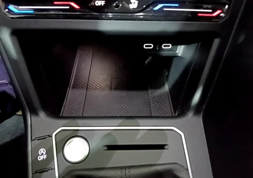 Gros plan sur la console centrale noire du Volkswagen Taigo 1.0 TSI 110 DSG R-Line avec boutons et ports USB visibles.