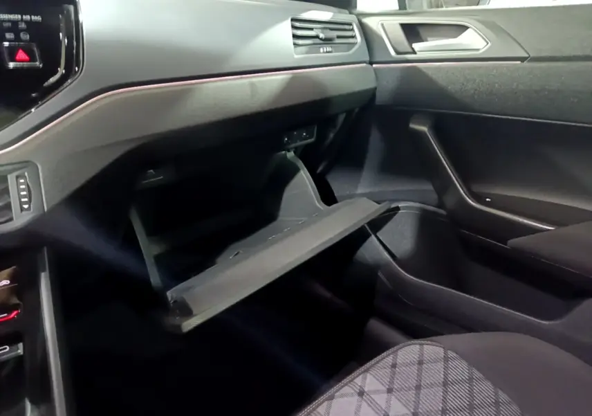 Vue intérieure côté passager du Volkswagen Taigo 2022, boîte à gants ouverte et tableau de bord noir avec finitions modernes.