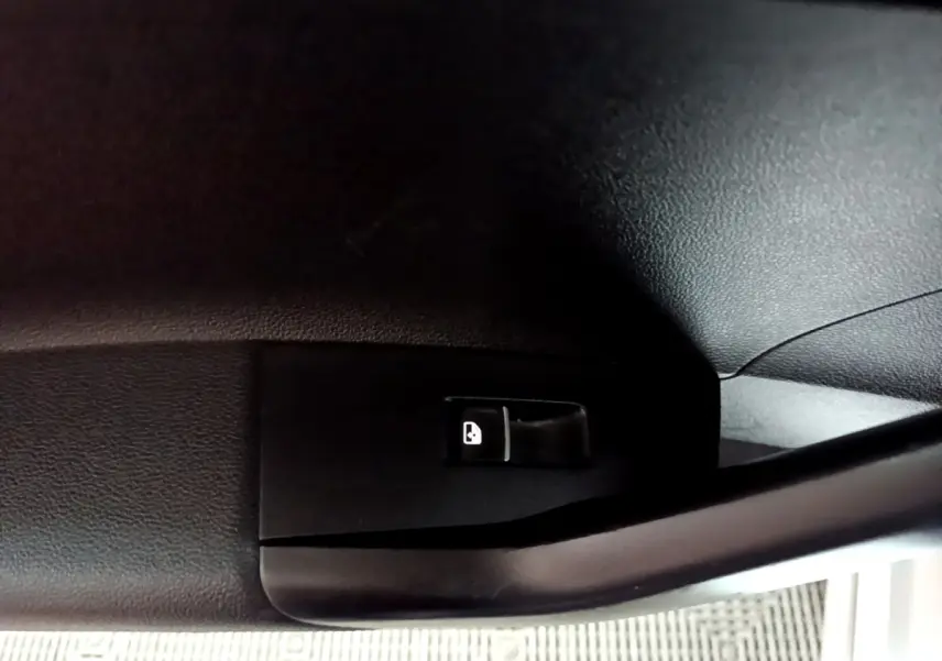 Gros plan sur le levier d'ouverture de trappe à carburant noir à l'intérieur d'un Volkswagen Taigo blanc.