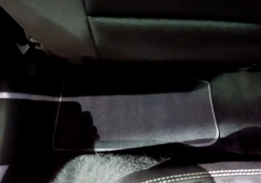 Vue intérieure du plancher arrière côté droit avec tapis noir et partie inférieure des sièges du Volkswagen Taigo blanc.