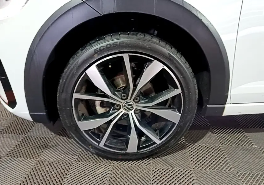 Gros plan sur la roue avant droite du Volkswagen Taigo blanc, mettant en valeur la jante alliage R-Line bicolore.