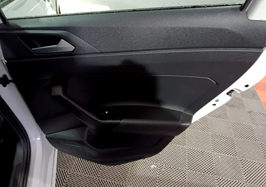 Vue rapprochée de la porte arrière gauche noire du Volkswagen Taigo blanc 2022, avec poignée intégrée.