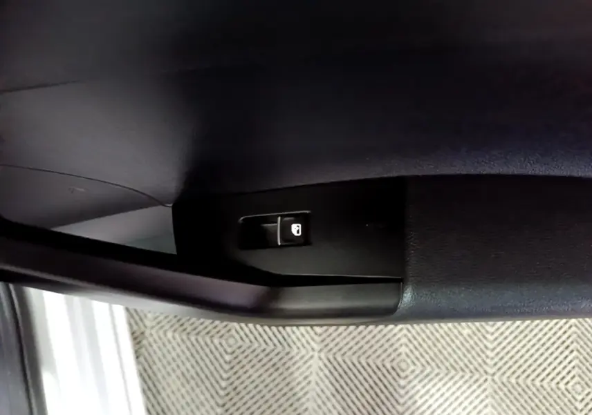 Gros plan sur le bouton de verrouillage de porte à l'intérieur d'une Volkswagen Taigo blanc, côté conducteur.