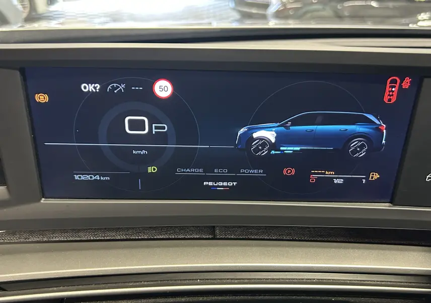 Affichage numérique du tableau de bord du Peugeot 5008 hybride 2025, avec vue latérale bleue du véhicule et indicateurs de vitesse et énergie.