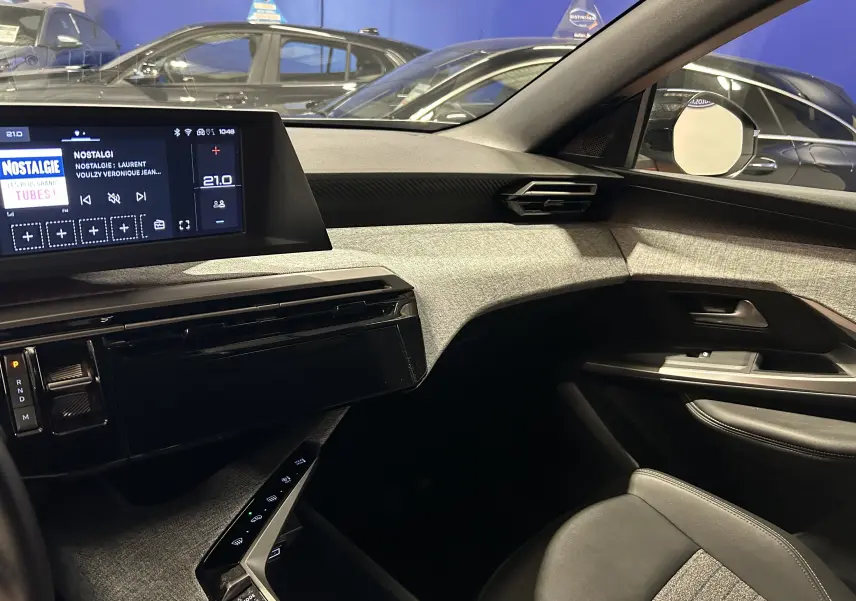 Vue intérieure côté passager du Peugeot 5008 gris Artense, mettant en valeur la planche de bord moderne et l'écran tactile.
