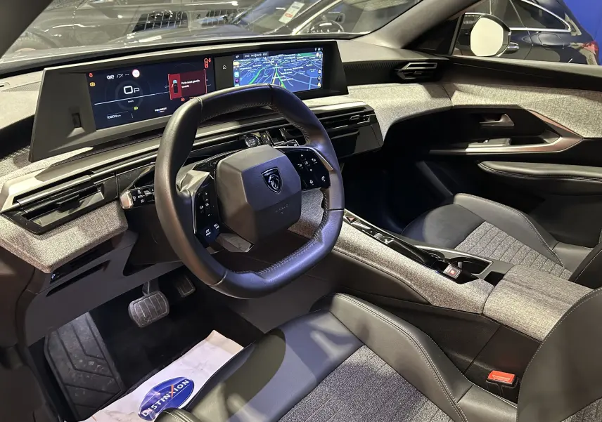 Intérieur du Peugeot 5008 III Hybrid 145 en gris Artense, vue côté conducteur avec tableau de bord numérique et volant cuir.