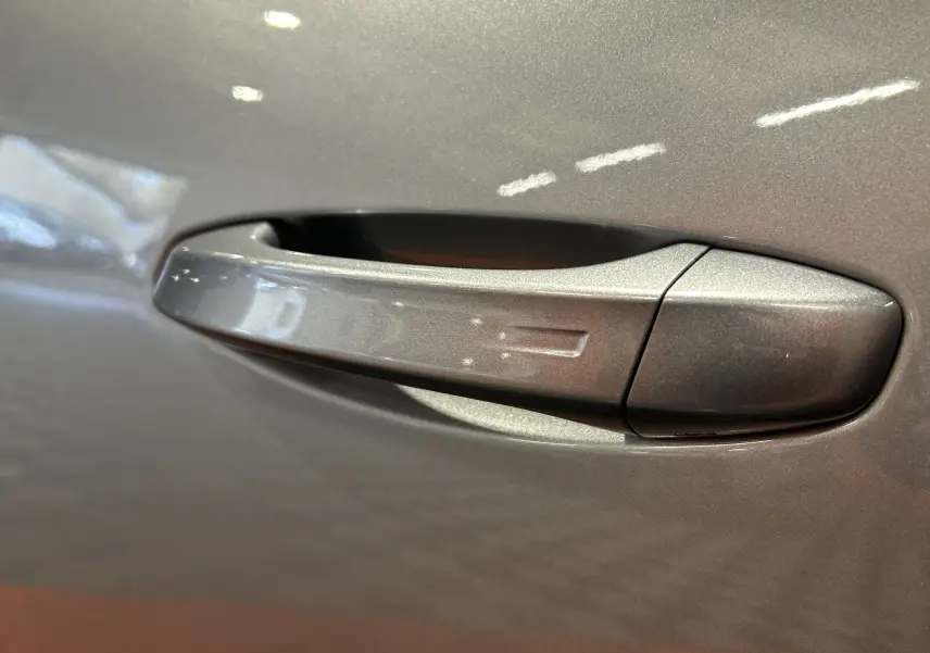 Poignée de porte gris Artense en gros plan sur Peugeot 5008 III Hybrid 2025, finition métallisée.