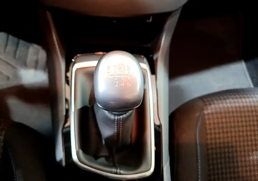 Le levier de vitesses manuel gris et noir de la Peugeot 308 Puretech 110 S&S Style vu de dessus, avec siège tissu à motifs.