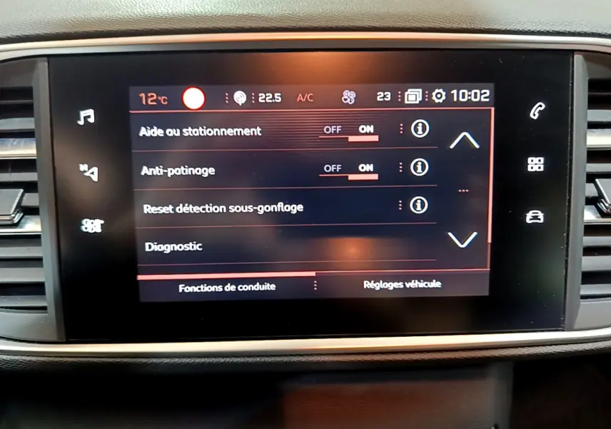 Écran tactile central affichant les réglages d'aide au stationnement et anti-patinage dans une Peugeot 308 gris clair de 2020.